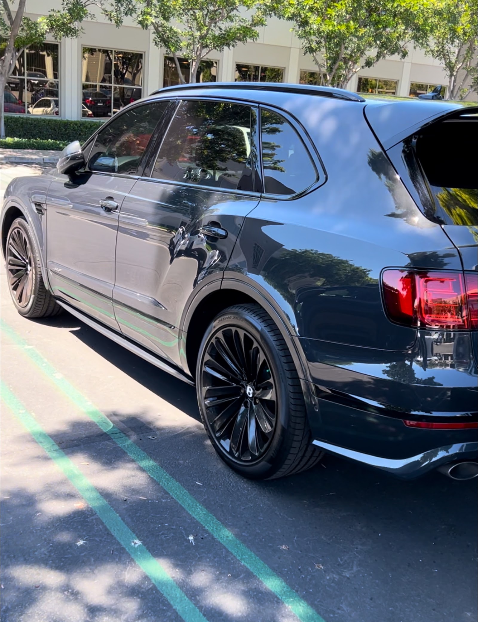 Rear side view of a dark Bentley Bentayga with glossy detailed finish