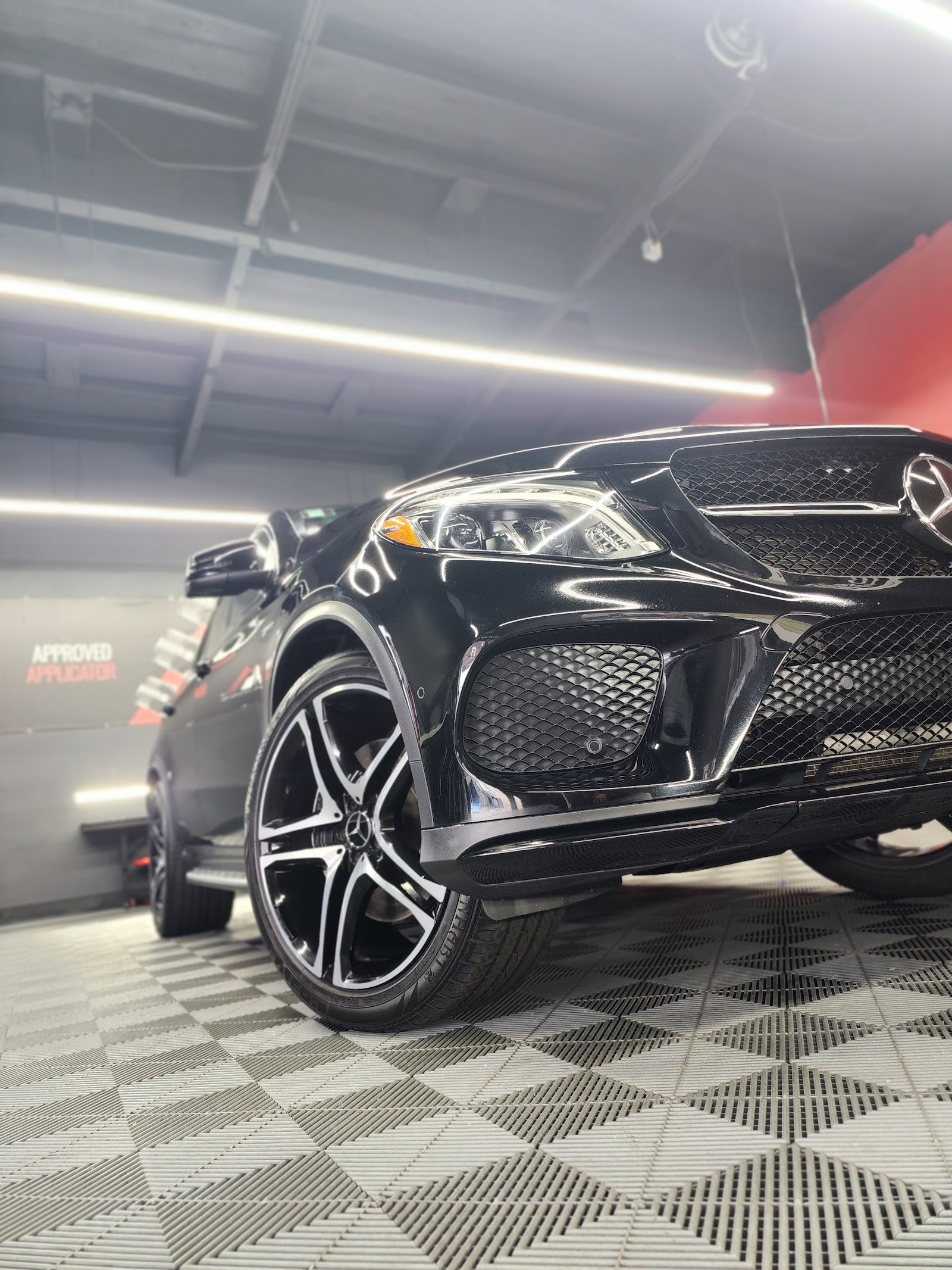 Front detail of a black Mercedes-Benz SUV with polished wheel in detailing studio